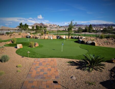 A golf course with a putting green and brick path.